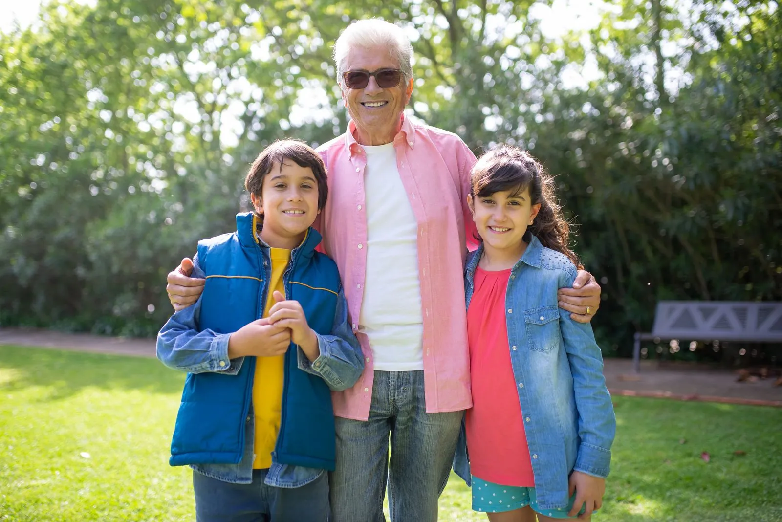 Grandfather standing with his grandchildren in a sunny park