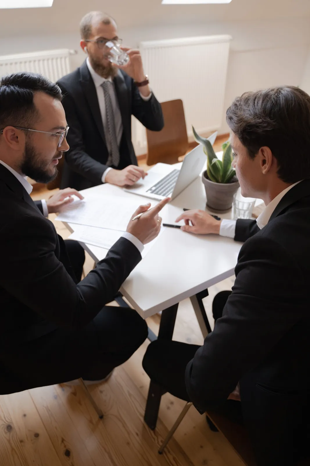 Three business owners in suits in a serious meeting around an office table