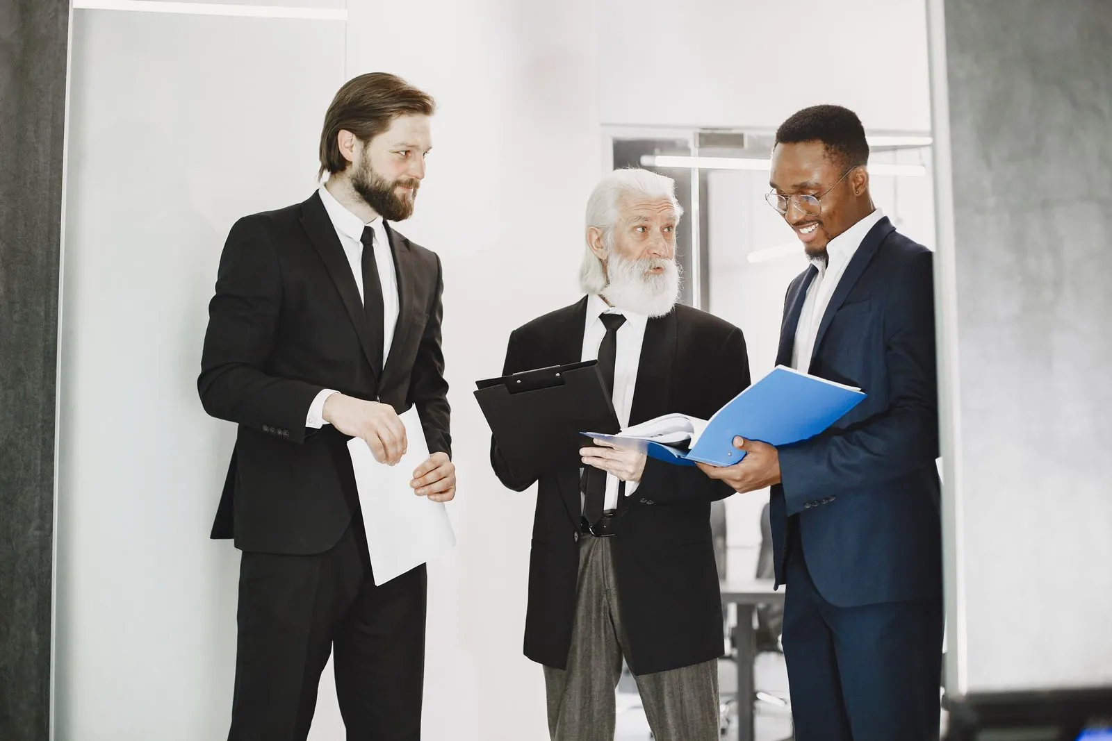 Three businessmen in suits reviewing deal documents